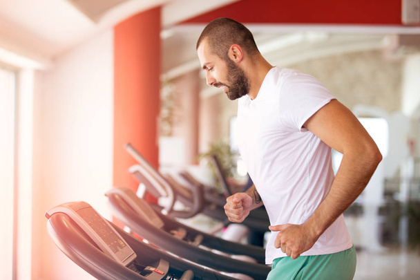 Man running in a modern gym on a treadmill. - Fotoğraf, Görsel