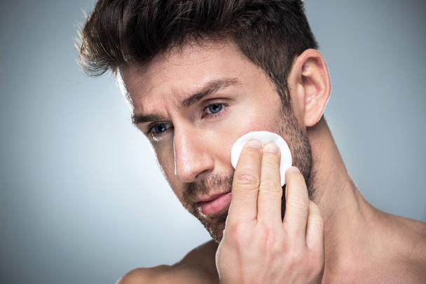 Man using cotton pad on face - Zdjęcie, obraz