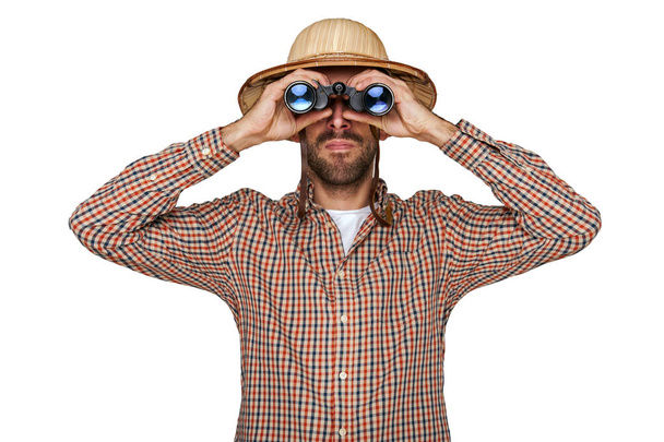 Man op zoek verrekijker met reiziger hoed geïsoleerd over witte bac - Foto, afbeelding