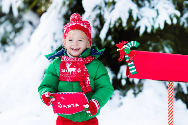 Bambino con lettera a Babbo Natale cassetta postale in neve
 - Foto, immagini
