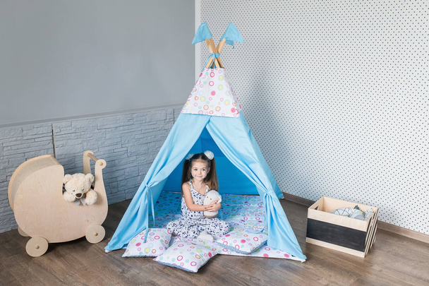 Child playing with a teepee tent - Foto, afbeelding