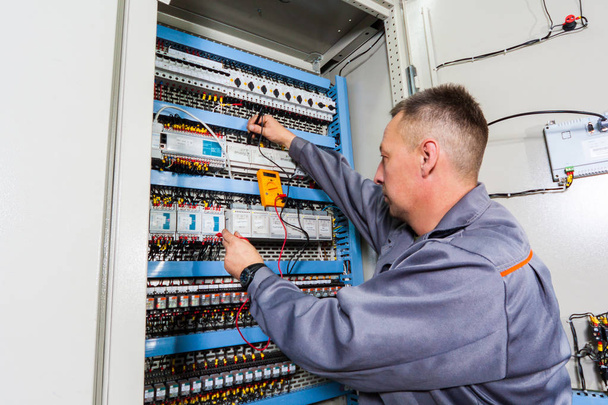 electrician testing industrial machine, electrician builder engineer screwing equipment in fuse box, Male Electrician - Photo, Image