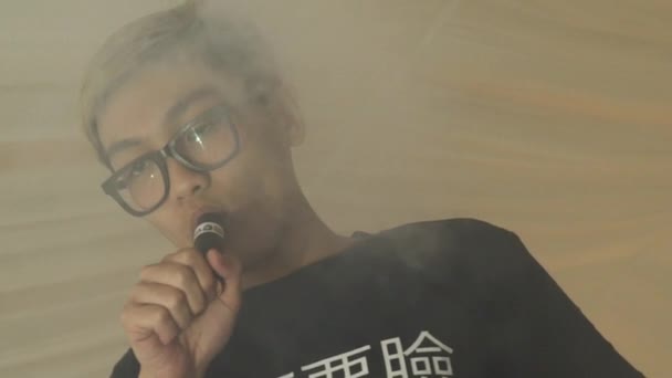 Asijský mladík v brýlích výdech dvojité kroužky z elektronické cigarety. Vaper. - Záběry, video