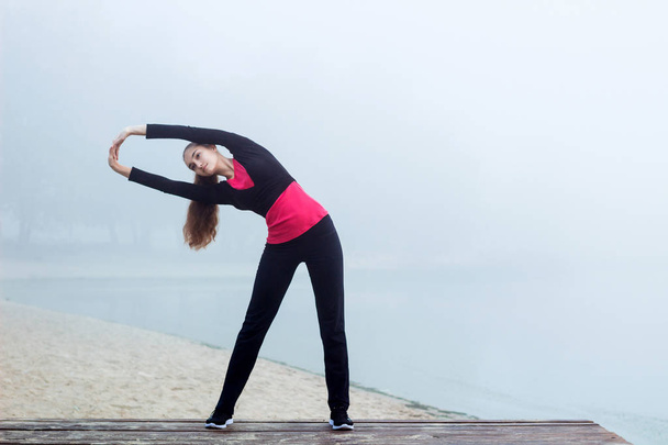 Νέοι σπορ γυναίκα κάνει τεντώνοντας ασκήσεις κατά τη διάρκεια της γυμναστικής tra - Φωτογραφία, εικόνα