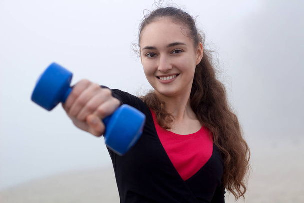 Jeune femme sportive faisant de l'exercice avec des haltères pendant le fitness train
 - Photo, image