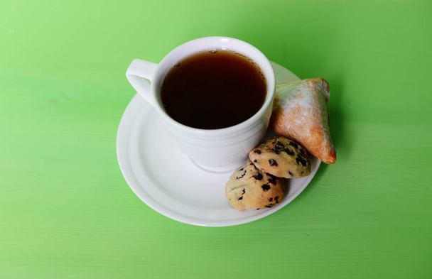 Una taza de té blanco. En el platillo hay galletas. Junto a una taza de hojas secas, manzanas y mandarina
. - Foto, imagen