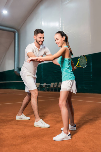 Professioanl instructor teaching young slim woman to play tennis - Foto, Imagem