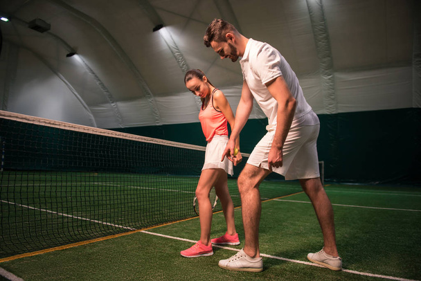 Instructor profesional enseñando a la joven a jugar al tenis
 - Foto, imagen