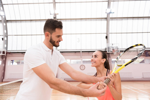 Professional handsome instructor showing woman how to play tennis - Φωτογραφία, εικόνα