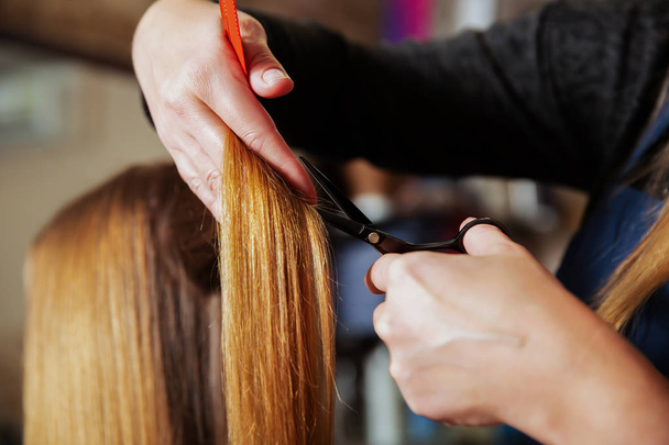 Hairdresser making hairstyle with scissors - Fotó, kép