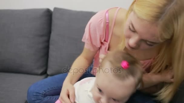 Mother with baby playing on couch - Záběry, video