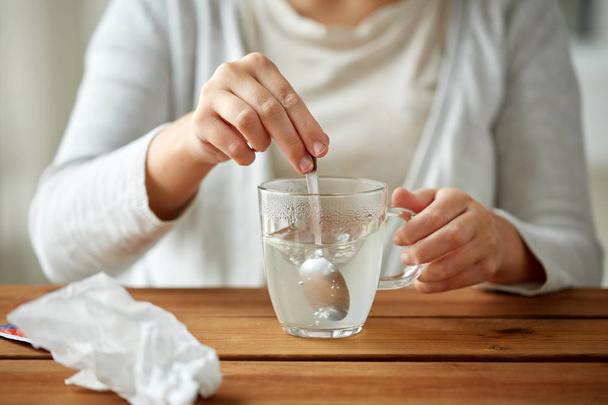 女性の薬をカップでスプーンでかき混ぜ - 写真・画像