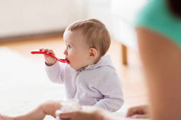 mother and baby with spoon eating at home - Foto, imagen