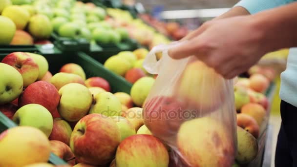 woman putting apple to bag at grocery store - Metraje, vídeo