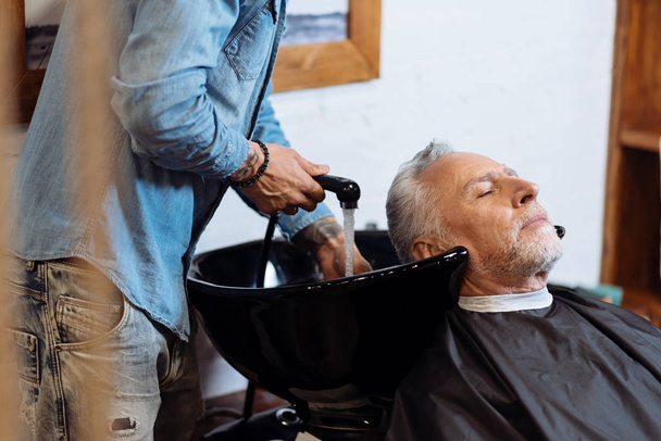 Senior man during washing hair in barbershop - Fotoğraf, Görsel