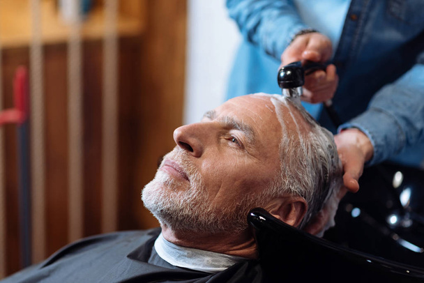 Old man during washing his hair in barber shop - Fotó, kép