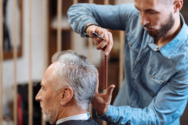 Hairdresser doing haircut to senior man - Foto, Imagen