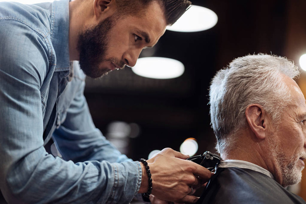 Hairdresser trimming neck of senior client - Фото, зображення