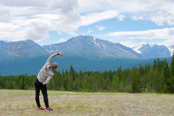 Male runner stretching outdoors at mountains background. Standing quadriceps quad stretch. Walking Heel to Butt. - Photo, image