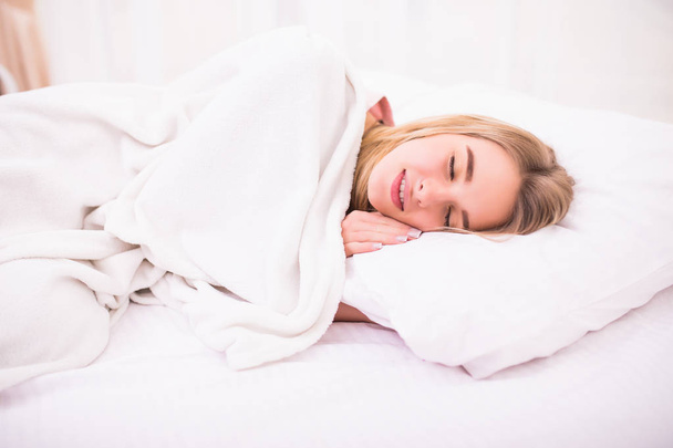 Нежная милая молодая женщина с длинными белыми волосами, лежащая и спящая в постели
 - Фото, изображение