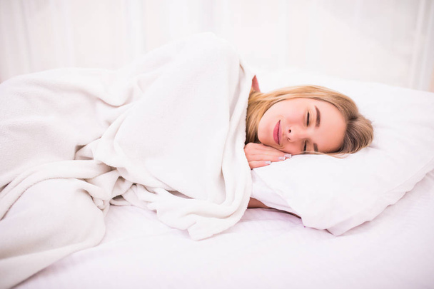 Inschrijving leuke jonge vrouw met lang wit haar liggen en slapen in bed - Foto, afbeelding