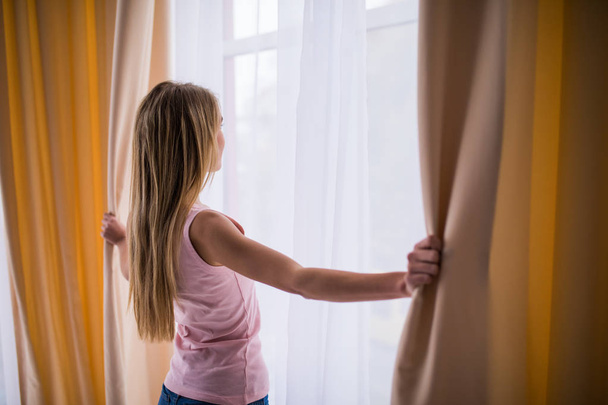 Menina loira jovem janelas abertas blinders em seu quarto
 - Foto, Imagem