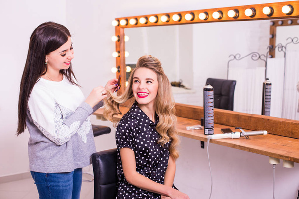 жіночий перукар стоїть і робить зачіску милою молодою жінкою в салоні краси
 - Фото, зображення