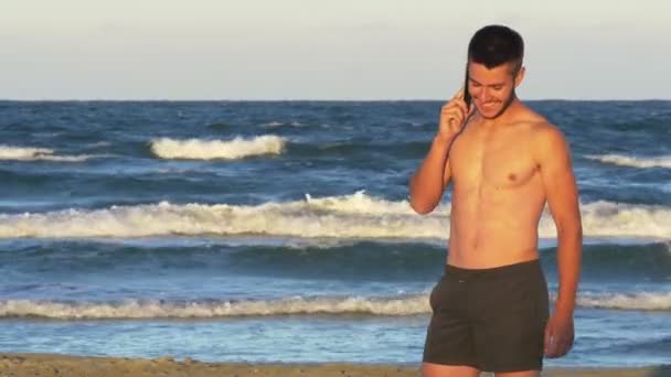 Komea nuori mies puhuu puhelimessa ottaa meren taustana
 - Materiaali, video