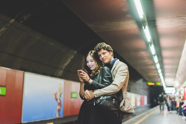 pareja enamorada usando smartphone en metro
 - Foto, imagen