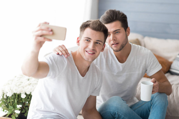 Young smiling gay couple taking selfie. - Valokuva, kuva
