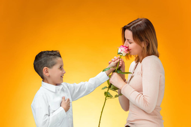 Young kid giving red rose to his mom - Foto, afbeelding
