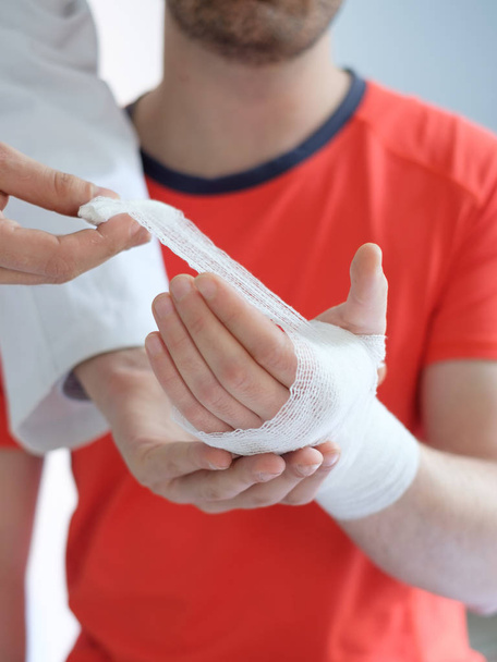 Arzt bandagiert einem Sportler nach einem Unfall die Hand - Foto, Bild