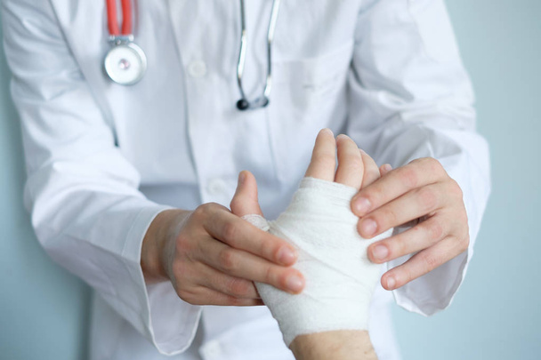 close up of doctor bandaging one hand after an accident - Photo, Image