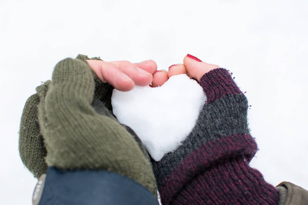 Пара рук тримає снігову кулю у формі серця
 - Фото, зображення