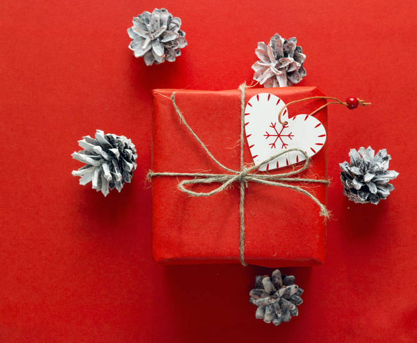 Червона подарункова коробка з конусами на червоному тлі. Різдвяний фон
 - Фото, зображення