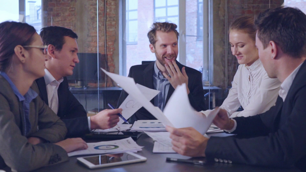 liikekumppanit keskustelevat asiakirjoista ja ideoista kokouksessa - Materiaali, video