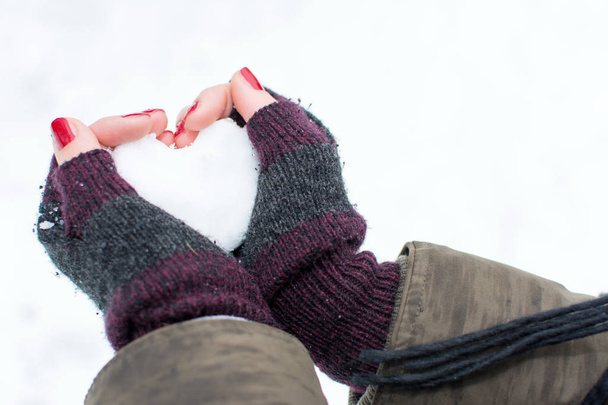 Руки жінки тримають снігову кулю у формі серця
 - Фото, зображення