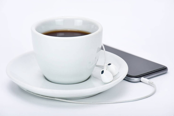 Чашка чая с мобильным телефоном и наушниками
 - Фото, изображение
