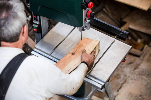 Man grinds wooden log  - Фото, изображение