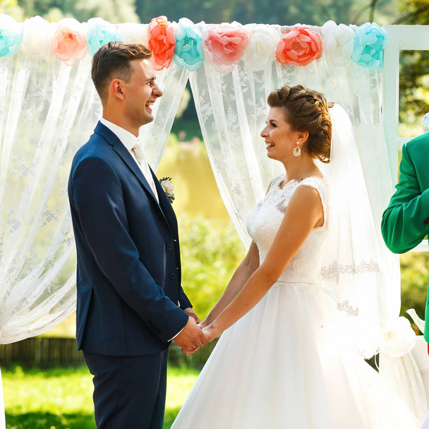 Brides hold hands near wedding archway - Φωτογραφία, εικόνα