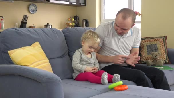 playful father have fun with baby girl on sofa at home. Man tickle toddler girl - Footage, Video