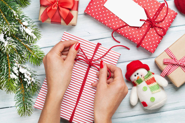 Mains féminines enveloppant cadeaux de Noël
 - Photo, image
