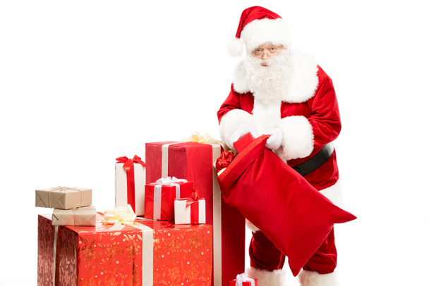 Santa Claus taking out Christmas gifts from sack - Foto, Imagen