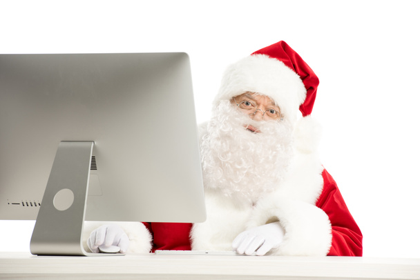 Santa Claus sitting at the desk with computer  - Foto, Imagen