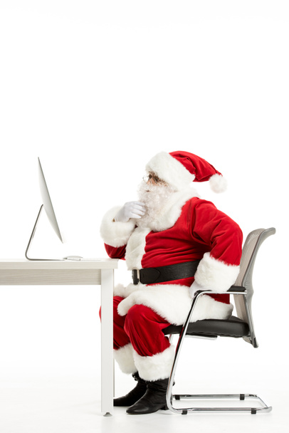 Thoughtful Santa Claus looking at computer - Zdjęcie, obraz