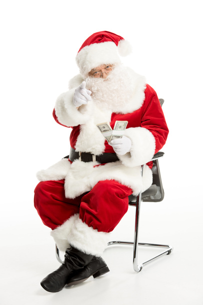 Papai Noel sentado com dólares na mão
  - Foto, Imagem