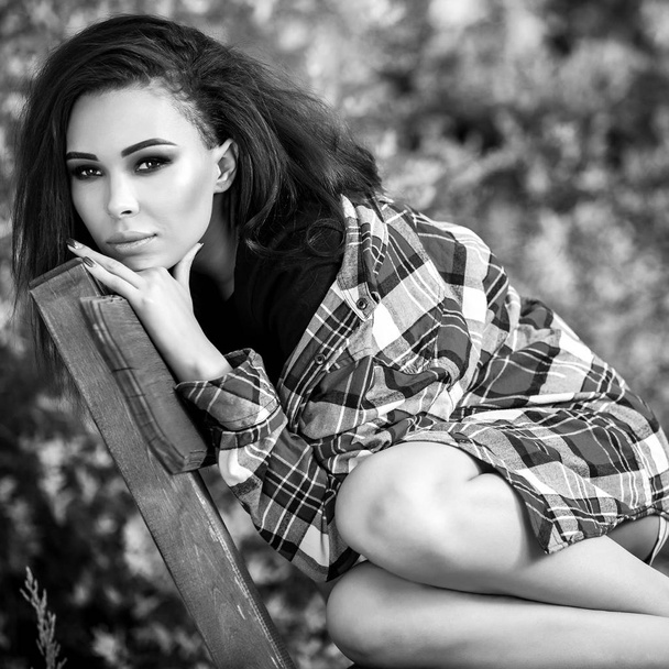 Black-white outdoor portrait of siting beautiful young brunette woman. - Photo, Image