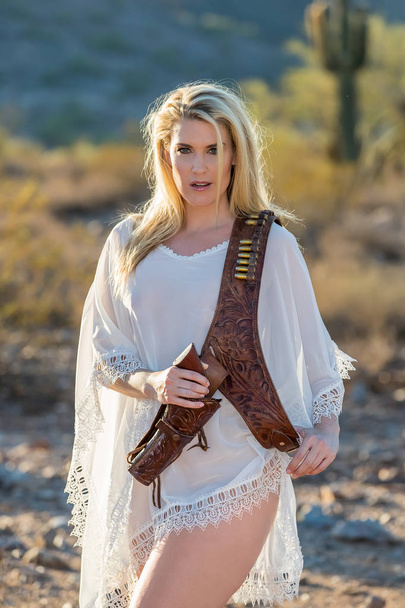 Blonde Model in woestijn met pistool - Foto, afbeelding