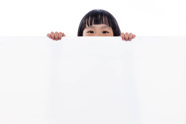 Asiática china pequeña niña espiando detrás de blanco tablero
 - Foto, Imagen