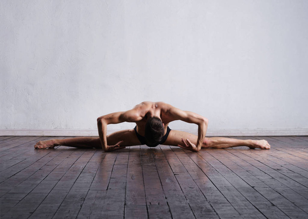Handsome ballet dancer sitting on split - Zdjęcie, obraz